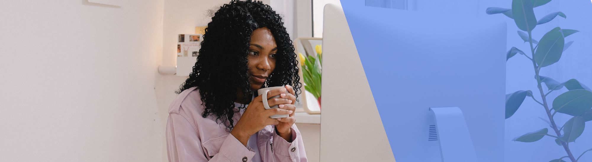 Woman sipping coffee looking at computer screen