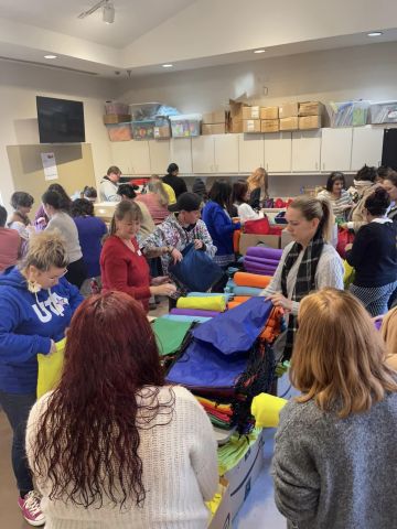 Photo of many Denton County Homeless Coalition members stuffing donation bags for PIT Count at Monsignor King Outreach Center